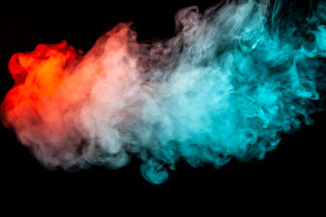 Multicolored dense illuminated smoke rolling from blue to red along substance molecules swirls on a black background, scattering in waves.