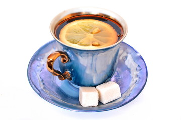 Vintage elegant stylish graceful beautiful porcelain cup with golden handle and two pieces of sweet sugar on dish of morning tea with lemon on white background. Isolated