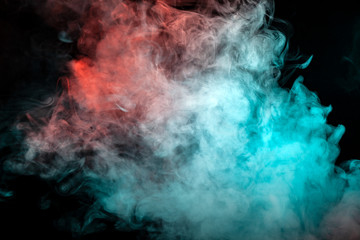A scattering white cloud of dense smoke, illuminated by different colors and exhaled from a...