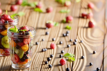 Assorted berries in mason jar on kitchen wooden table