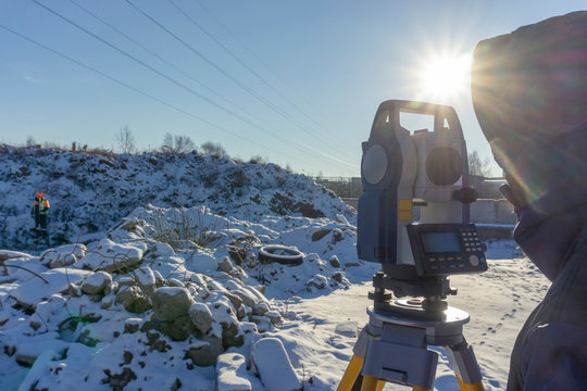 Surveyor and assistant conduct a topographical survey in the winter for cadastral work