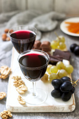 Creme de Cassis homemade liqueur served with grapes, nuts and chocolate. Rustic style.