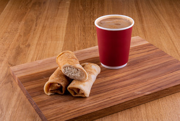 Pancakes with meat on a wooden board with a cup of coffee