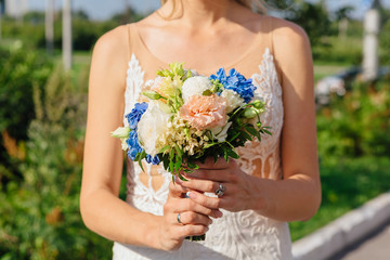 Bride holding wedding bouquet ourdoors. Close up.