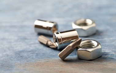 Bits for a screwdriver and hex nuts on wooden background. Close up. Copy space. 
