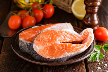 Cooking two fresh raw salmon fish steaks on wooden rustic table closeup