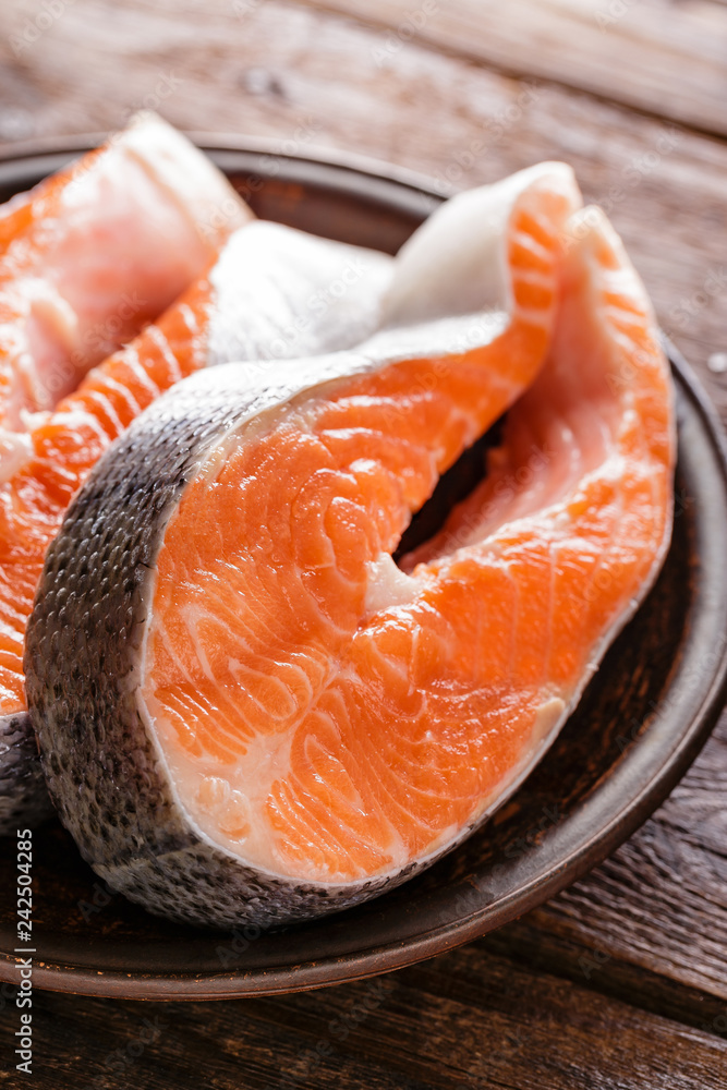 Poster cooking two fresh raw salmon fish steaks on wooden rustic table closeup