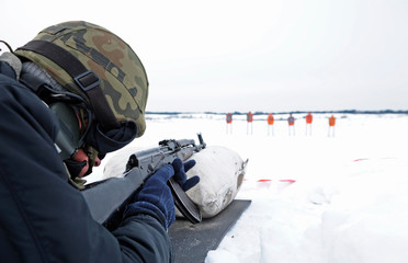 Fototapeta na wymiar Soldier aiming on marks with Kalashnikov rifle