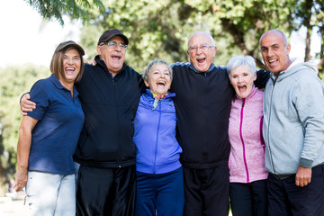 Gruppo di anziani felici che si abbracciano al parco dopo aver fatto attività fisica