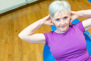 Donna in tuta ginnica di età maturata le flessioni per gli addominali