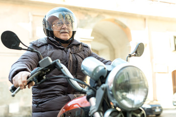 Anziano motociclista in sella alla sua moto con casco 