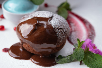 Chocolate fondant with blue ice cream, on a white plate, with mint and berries