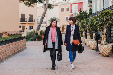 Two happy friends walking towards camera and talking on the street. Lifestyle outdoors