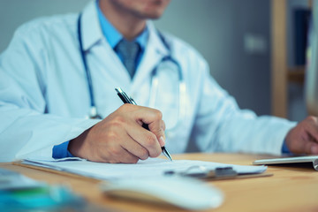 Doctor with Stethoscope clipboard and Laptop on desk,working in hospital writing a prescription, Healthcare and medical concept,test results in background,vintage color