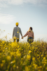 Loving couple in meadow admiring the view - obrazy, fototapety, plakaty
