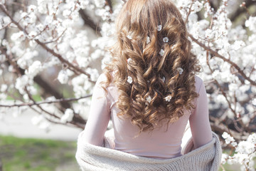 Woman with curly hair outdoors on spring background. Unrecognizable lady with blonde and long healthy hair. Girl haircut closeup still