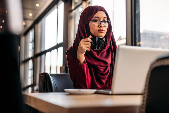 Muslim woman working on laptop at a cafe