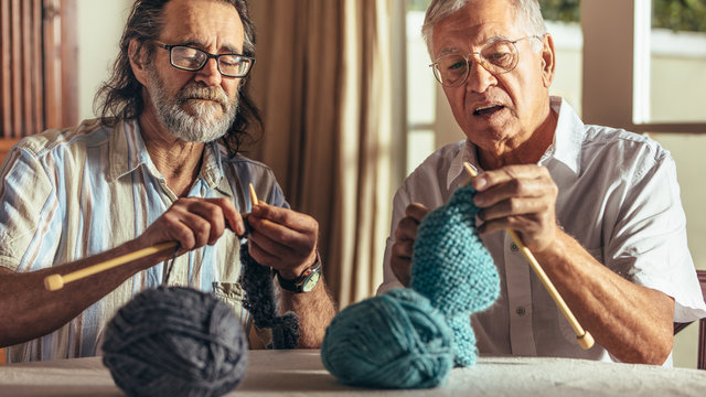 Two senior friends knitting at home