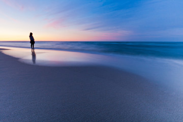 Fototapeta na wymiar Lonely person at sunset sea. Long exposure landscape
