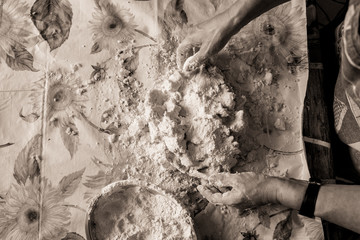 above view of young italian housewife woman hands making fresh homemade italian pasta on table with flour with vintage sepia effect