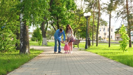 little baby learning how to walk with mom and dad helping him to make his first steps, happy family walking in summer Park