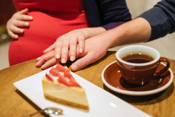 Fototapeta na wymiar Pregnant woman with husband relax in cafe and drink coffee