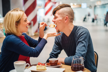 Pregnant woman with husband relax in cafe eat cake