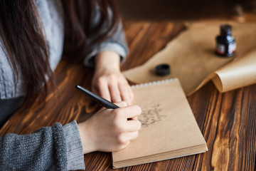 woman writes calligraphic handwriting on craft paper with ink pen