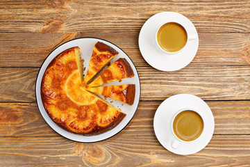 Homemade Pineapple Upside Down Cake and two cups of coffee espresso on wooden table. Top view.