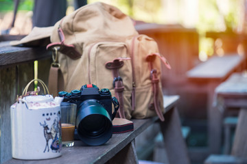 Cup of coffee, tea, camera and vintage camera bag on a wooden chair. Coffee break time of photographer.