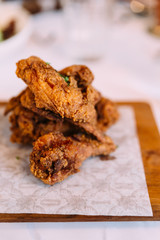 Hot and crispy golden Fried Chicken wings and wingsticks. Served on wooden plate.