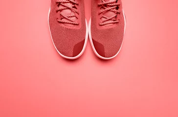 Trendfotografie zum Thema der neuen Farbe des Jahres 2019 - Living Coral. Paar lebende korallenrote Sportschuhe im Hintergrund © alimyakubov
