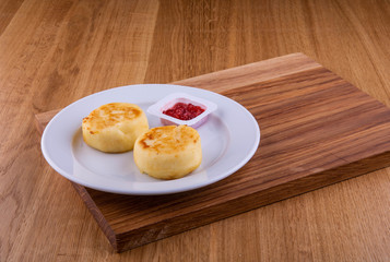 Strawberry jam with cheesecakes in a plate on a board
