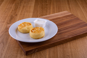 Cheesecakes, are served in a plate with sour cream
