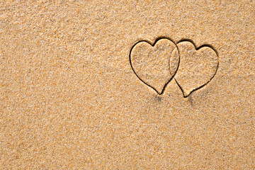 Two hearts drawn in the sand at the beach.