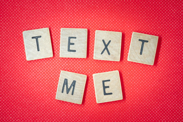 Text me wooden block words on red background