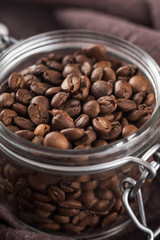 Glass jar with roasted coffee beans. Macro view. Closeup