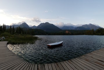 Деревянная лодка на горном озере  на фоне высоких гор 