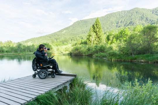 Disabled Person On Wheelchair Photographing At Lake In Nature