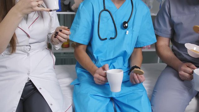 Three doctors in the staffroom talk and drink coffee at the break.
