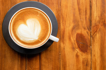 Latte art coffee with heart shape on wood table background. Top view.
