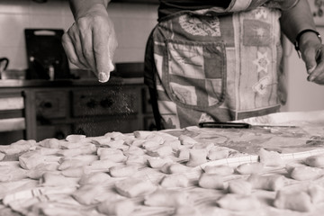 above view of young italian housewife woman hands making fresh traditional  homemade italian gnocchi pasta on table with flour sepia vintage effect