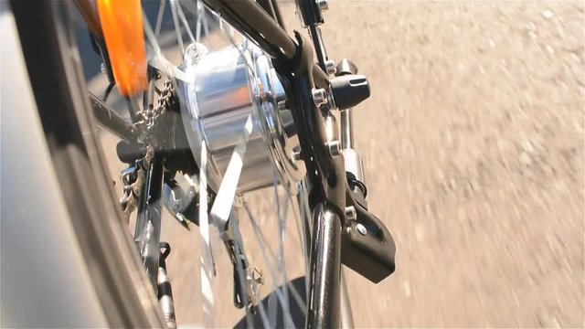 Electric bicycle motor spins close up. E bike motor rotation while riding without peddling in sunny summer day. Electric wheel in details.