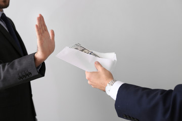 Businessman refusing to take bribe on light background. Concept of corruption