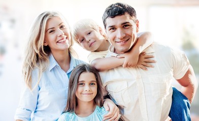 Beautiful smiling family sitting at sofa on background