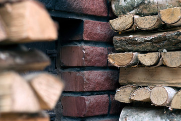 Birch firewood near the furnace firebox. Chipped logs lying near the stove of red brick