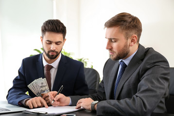 Man giving bribe to businessman in office. Concept of corruption