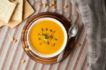 Pupmkin cream soup puree, Dietary vegetarian food on dark brown wooden table, top view, close up.