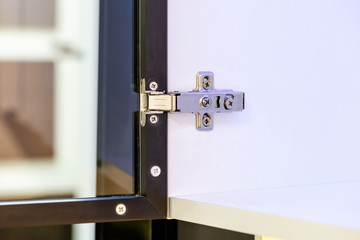 Closeup of an adjustable concealed hinge fixed on a cabinet with a glass door
