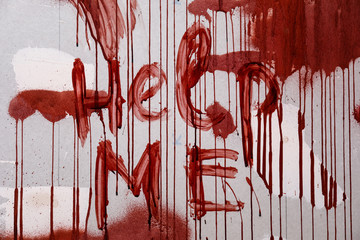 Text HELP ME written in blood on wall